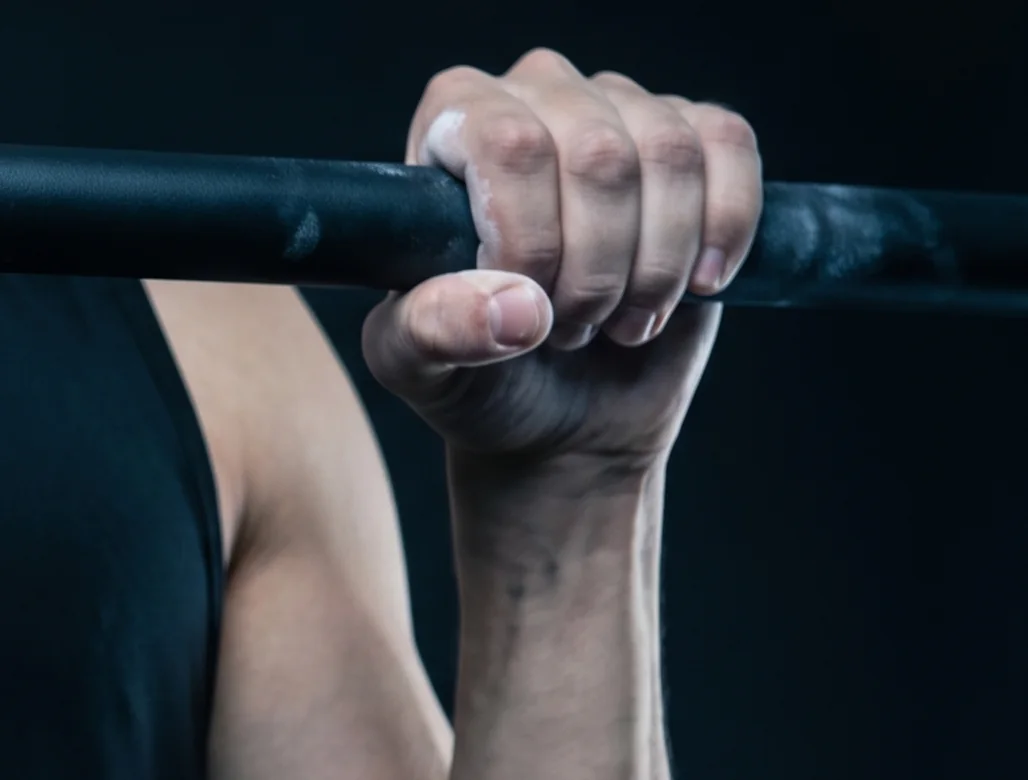 Chalked hand gripping a pull-up bar during grip endurance training
