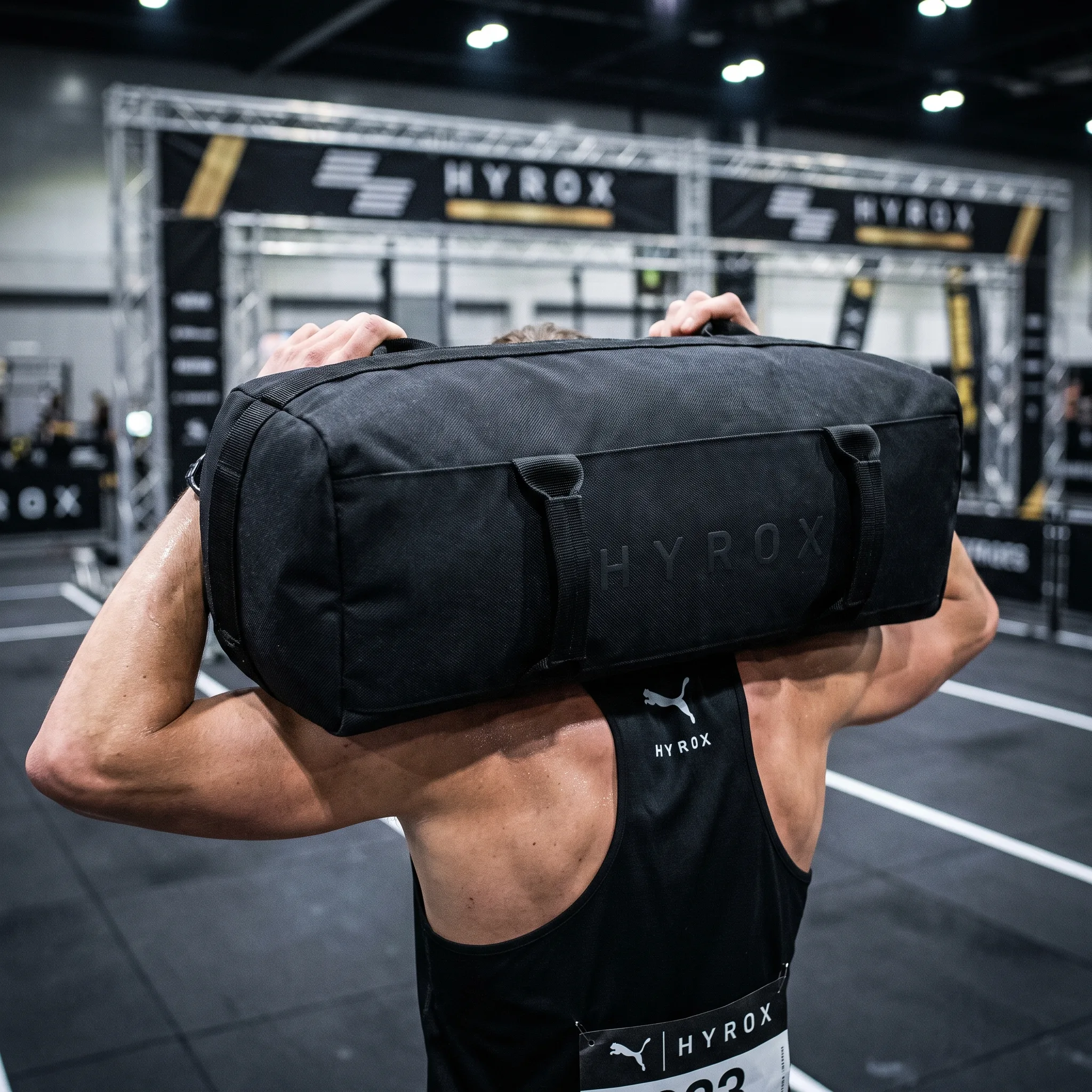 Correct HYROX sandbag position resting evenly across both shoulders behind the neck
