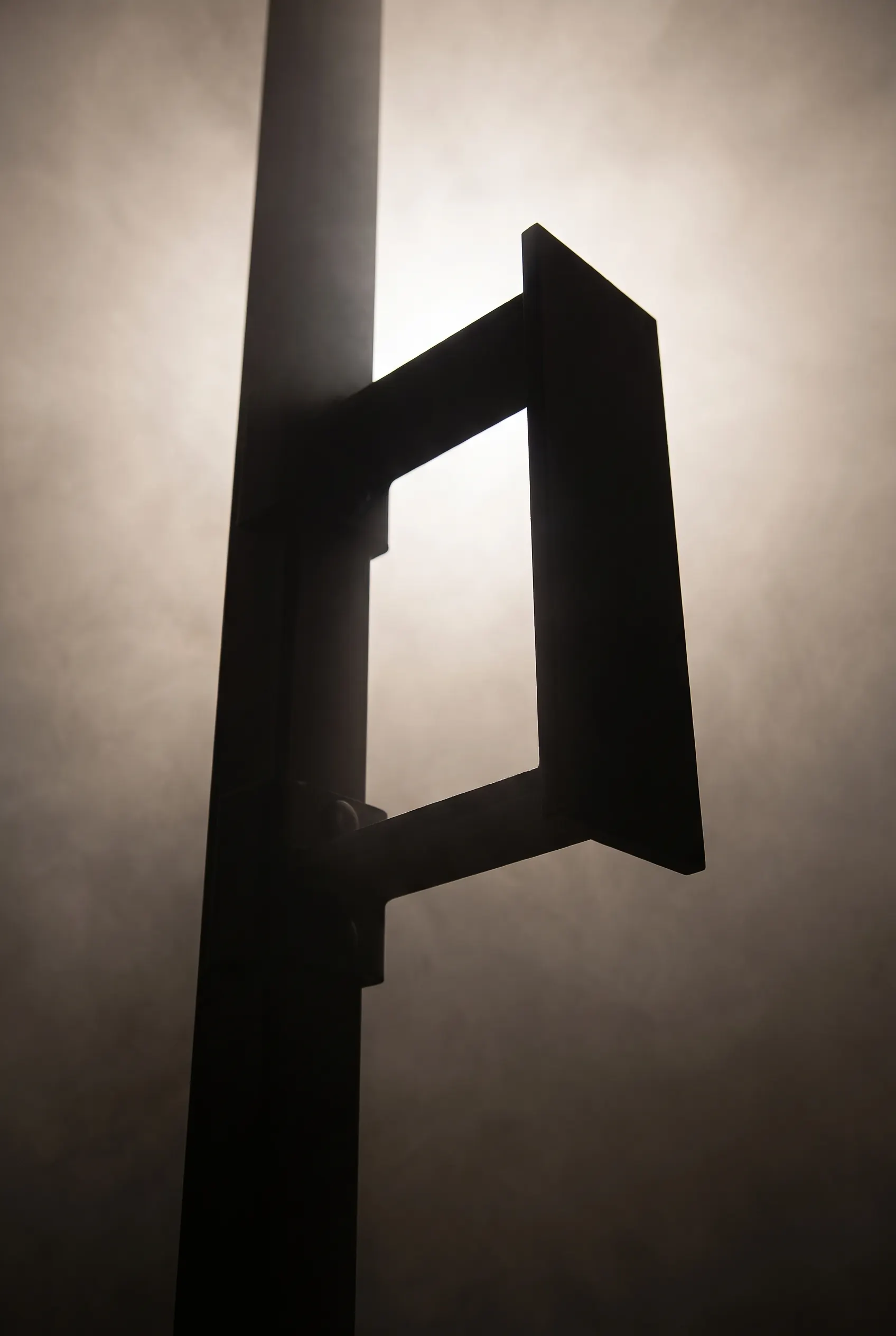 Backlit silhouette of a HYROX wall ball target mounted high on a single upright.